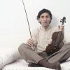 Franco Battiato sitting on the bed with a violin in his hand. 1981. (Photo by Angelo Deligio/Mondadori via Getty Images)